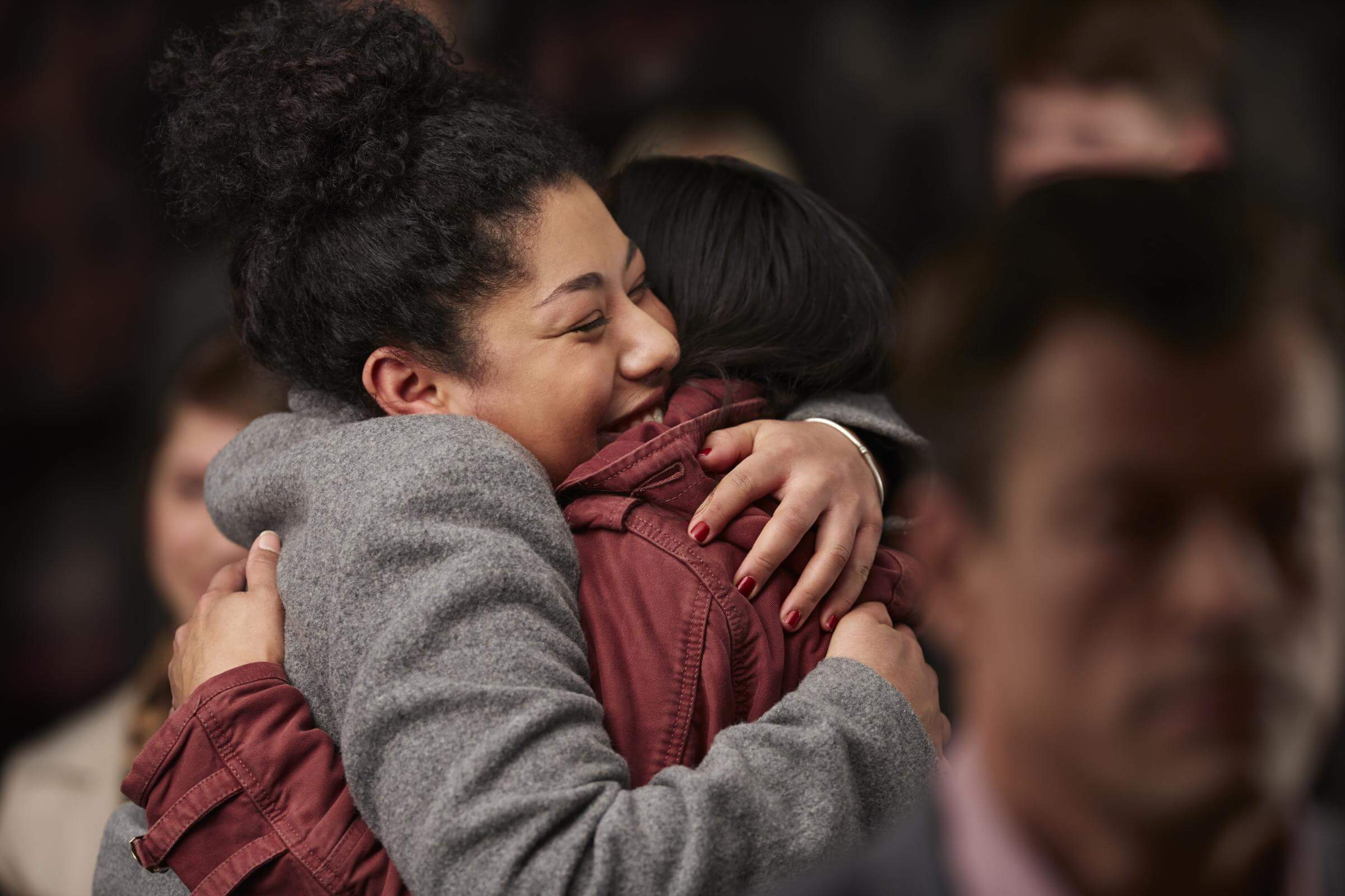 Two people embracing in a warm hug, surrounded by others